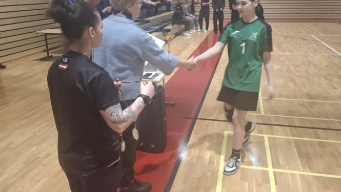 Basketbola komandas dalībniece saņem apsveikumu un apbalvojumu apbalvošanas laikā.