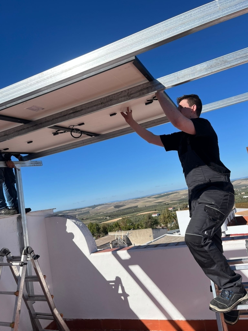 Daugavpils Tehnoloģiju un tūrisma tehnikuma elektrotehniķis Erasmus+ prakses laikā Spānijā piedalās saules paneļu montāžas darbos uz ēkas jumta.
