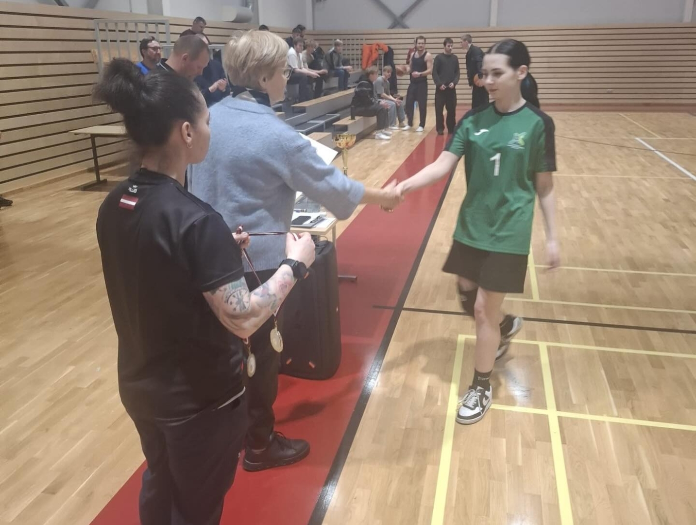 Basketbola komandas dalībniece saņem apsveikumu un apbalvojumu apbalvošanas laikā.