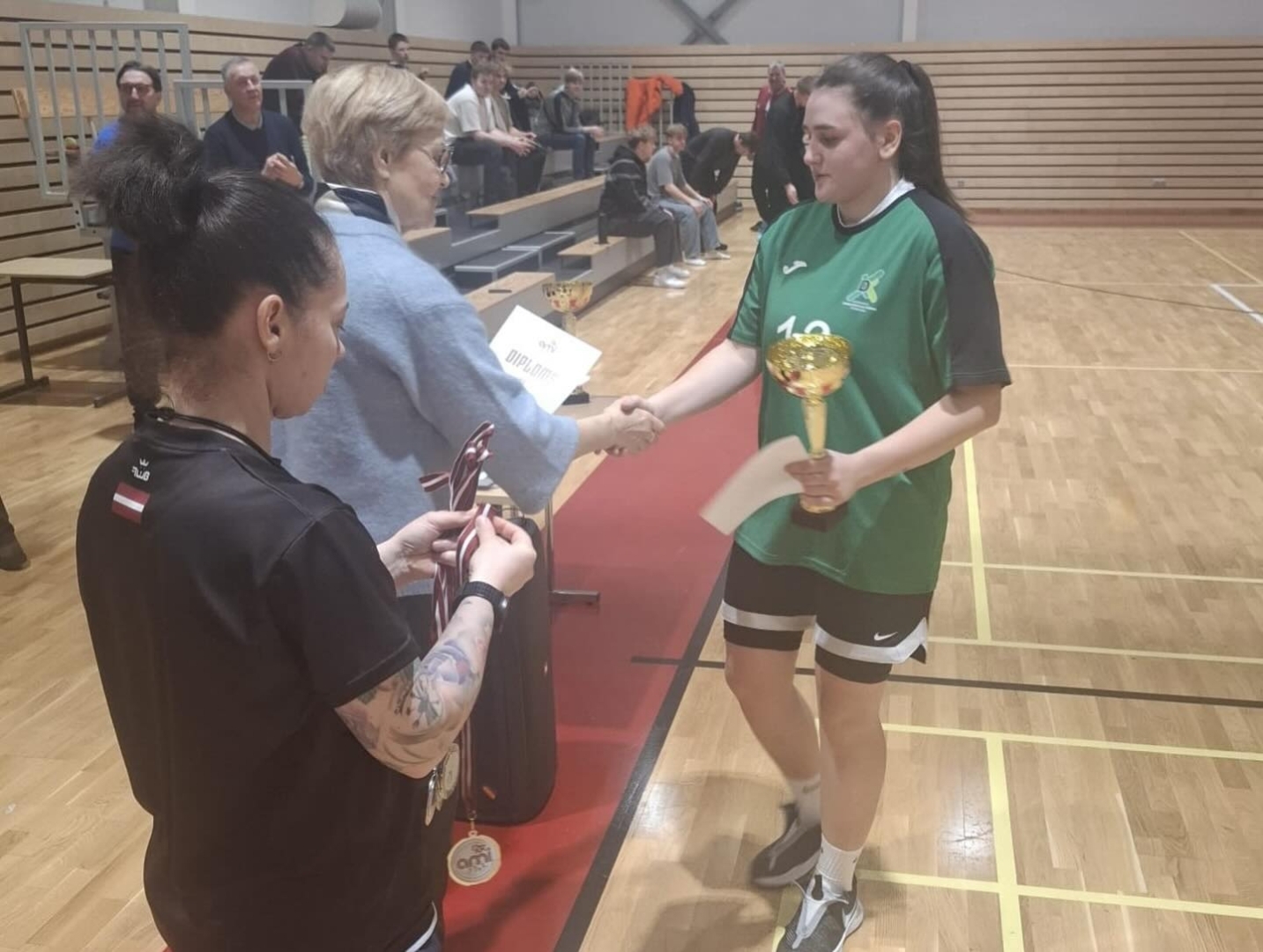 Basketbola spēlētāja saņem diplomu un medaļu Latvijas mēroga sacensībās.