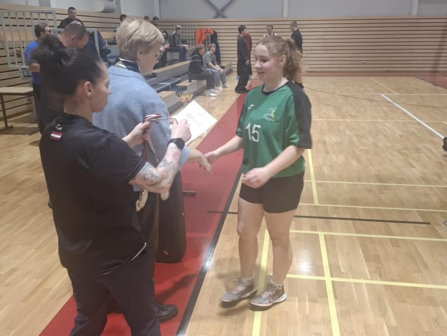 Apbalvošanas ceremonijas noslēgums ar spēlētāju dalību un skatītājiem sporta zālē.