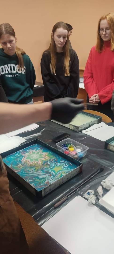 Izglītojamie vēro ebru gleznošanas procesu un gatavojas pārnest zīmējumu uz papīra