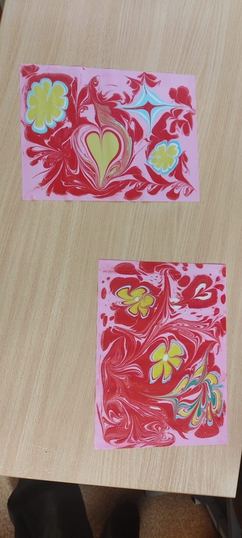 Ebru tehnikā veidoti krāsaini zīmējumi uz papīra ar sirds un ziedu motīviem