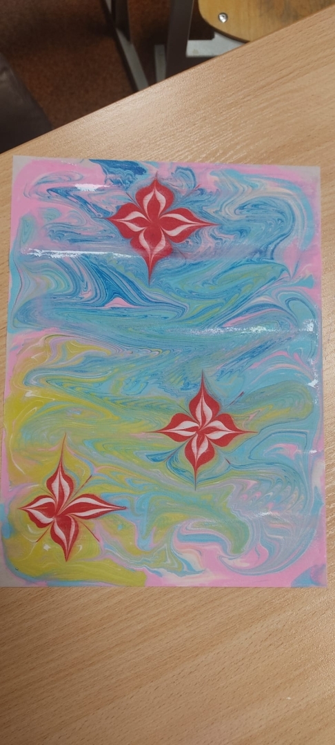 Gatavs ebru mākslas darbs ar abstraktiem rakstiem zilā, dzeltenā un rozā krāsā