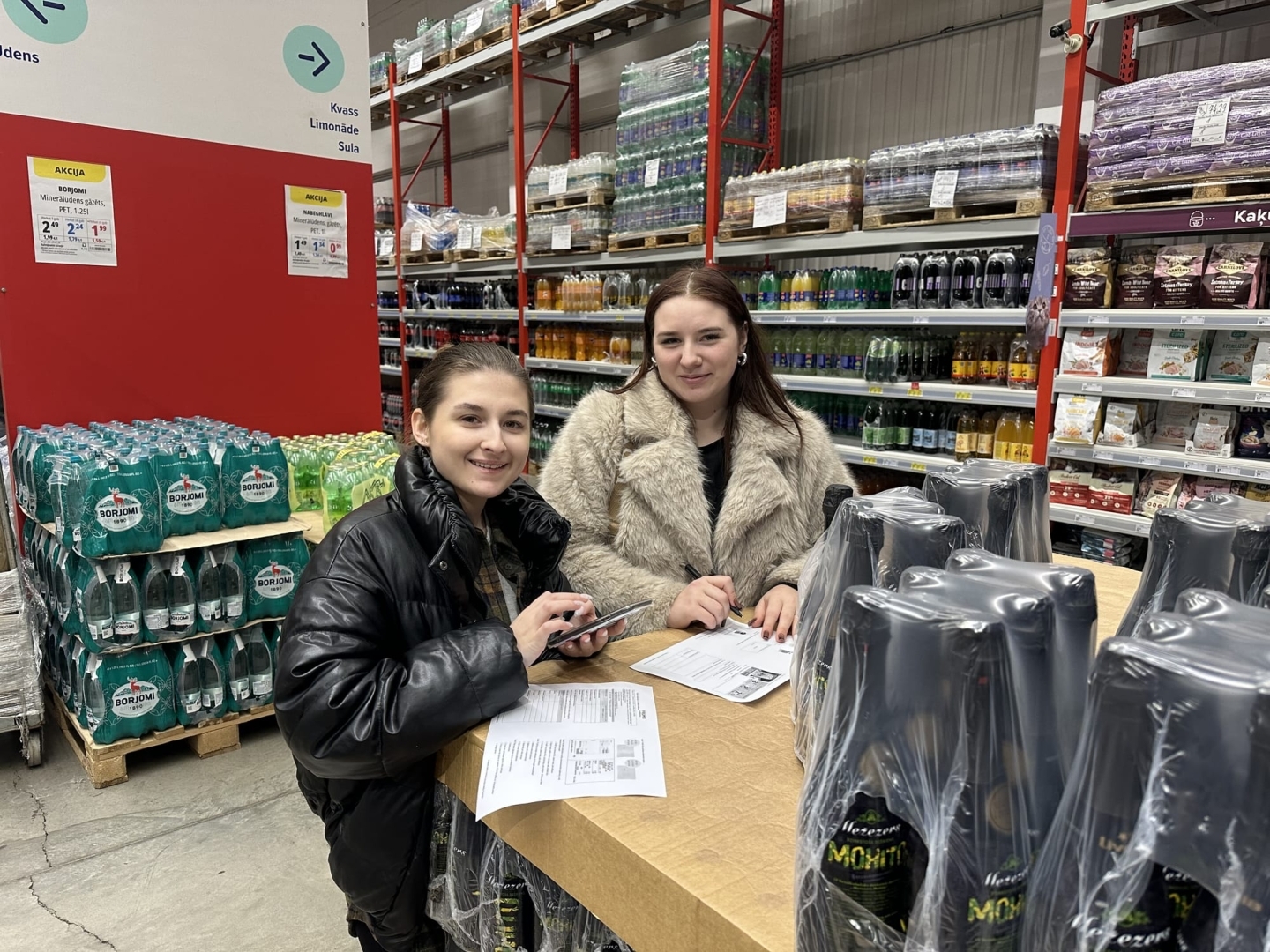 Izglītojamās ar uzdevumu lapām dzērienu nodaļā PROMO Cash&Carry veikalā