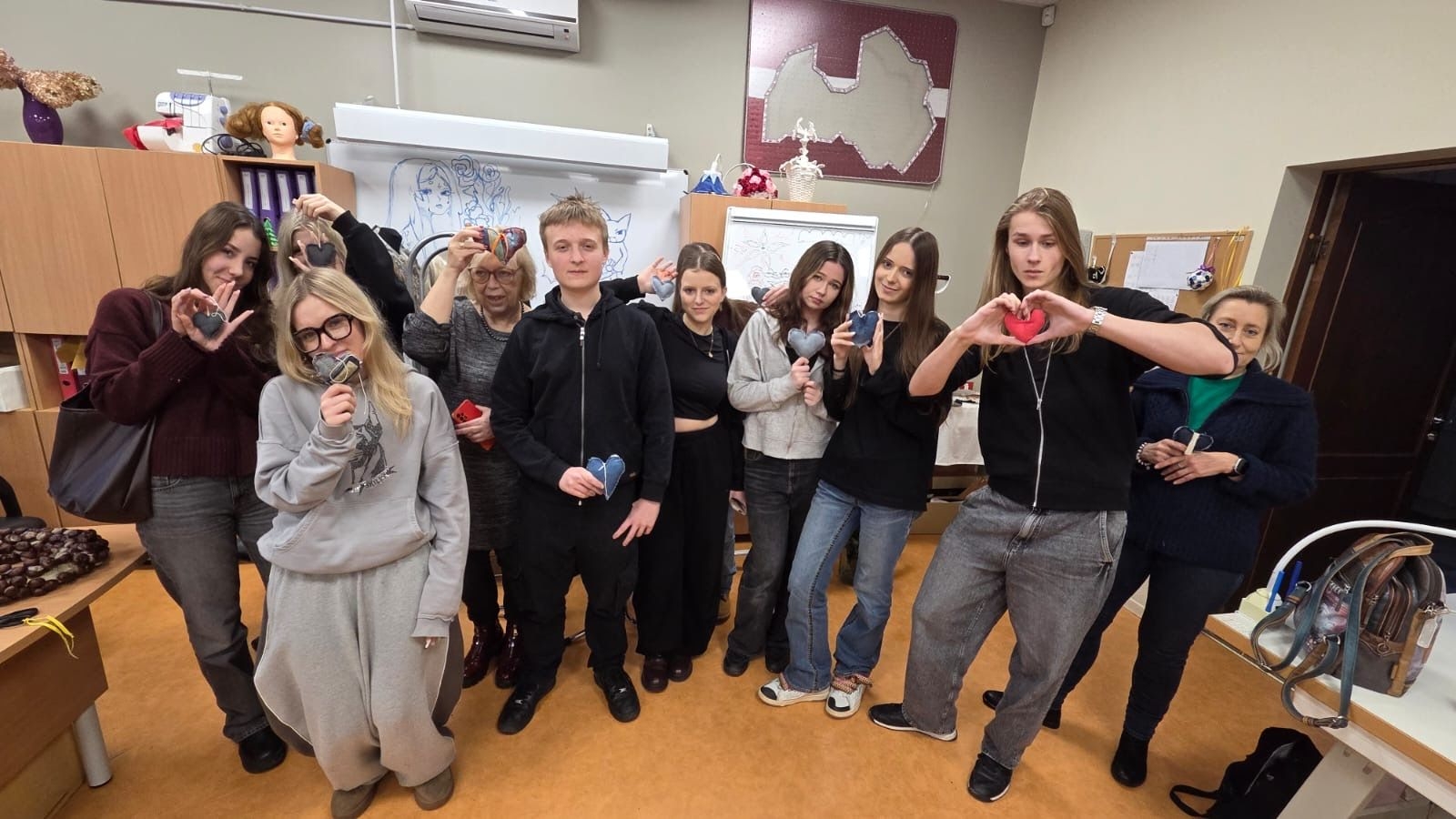 Latvijas un Polijas skolēni ar skolotājiem pozē kopbildē ar rokās turētām pašdarinātām sirsniņām