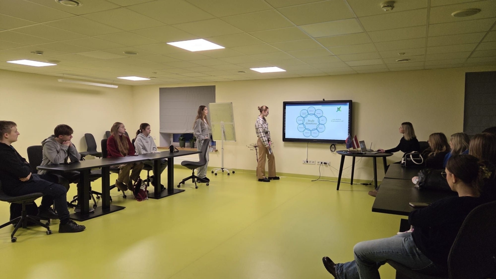 Skolēni piedalās prezentācijā un diskusijā mācību telpā pie interaktīvā ekrāna