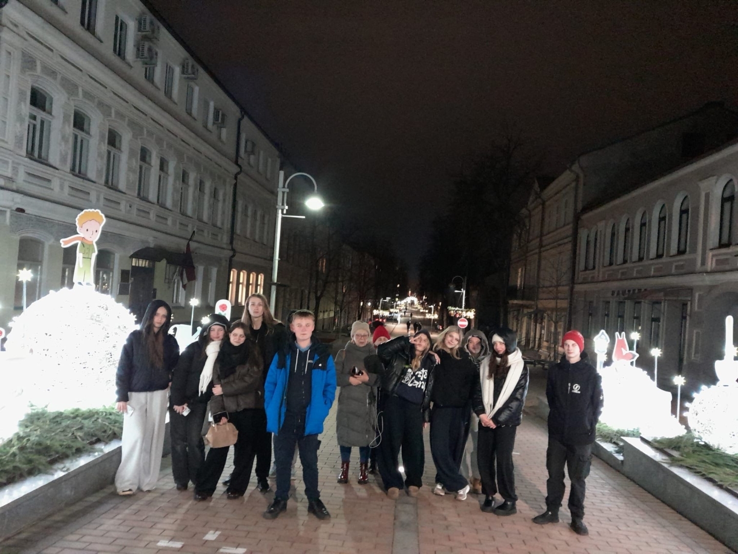 Latvijas un Polijas skolēni vakara pastaigā pilsētā pie svētku gaismas objektiem