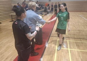 Basketbola komandas dalībniece saņem apsveikumu un apbalvojumu apbalvošanas laikā.