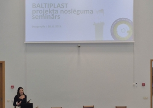 BALTIPLAST starptautiskā projekta noslēguma seminārs Daugavpilī – referente uzstājas auditorijā, fonā redzams prezentācijas ekrāns ar semināra nosaukumu un Eiropas Savienības līdzfinansējuma norādi (28.11.2025.).