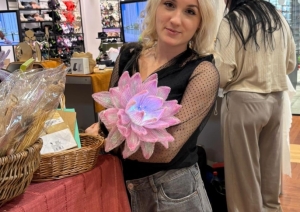 Skolēnu mācību uzņēmuma “Brīnumrotaļa” pārstāve demonstrē ar rokām veidotu dekoratīvu ziedu pasākumā “Cits Bazārs”.