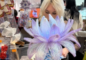 Detalizēts skats uz skolēnu mācību uzņēmuma “Brīnumrotaļa” dekoratīvajiem ziediem un rokdarbiem tirdzniecības stendā.