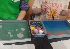 Skolēni ebru tehnikā glezno uz ūdens, izmantojot krāsas un otas meistarklases laikā