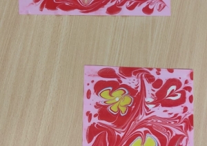 Ebru tehnikā veidoti krāsaini zīmējumi uz papīra ar sirds un ziedu motīviem