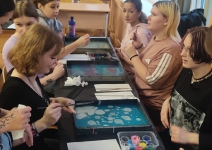 Skolēni klases telpā piedalās ebru meistarklasē un veido rakstus uz ūdens virsmas