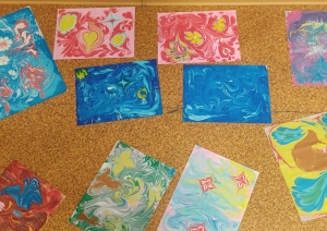 Skolēnu veidoto ebru darbu izstāde, izvietota uz grīdas, demonstrējot dažādus krāsu rakstus